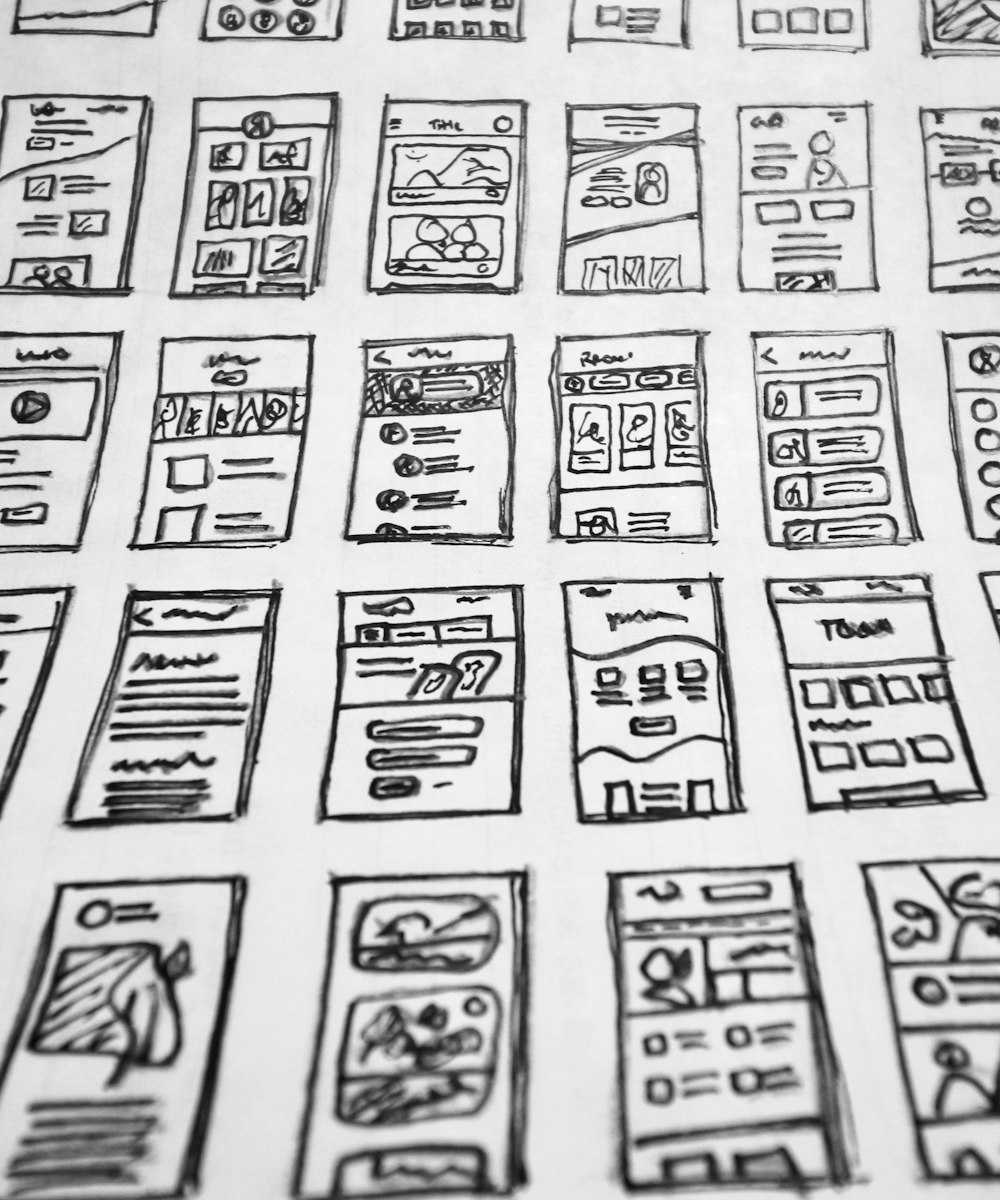Planches de wireframes d'interface dessinés au stylo sur papier — études d'écrans d'application.