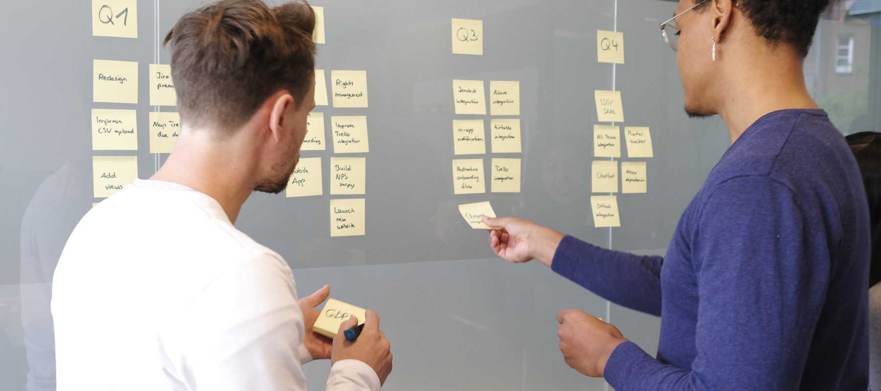Deux personnes devant un mur de post-its — séance de cadrage produit.